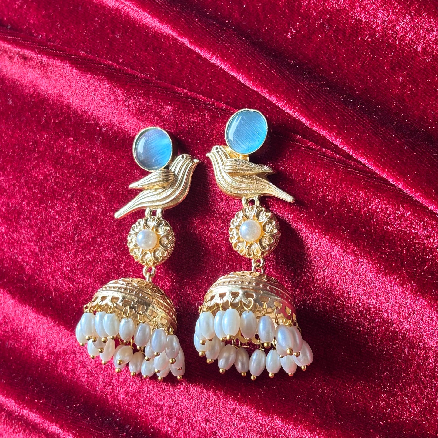 Gold and pearl earrings on a red velvet background