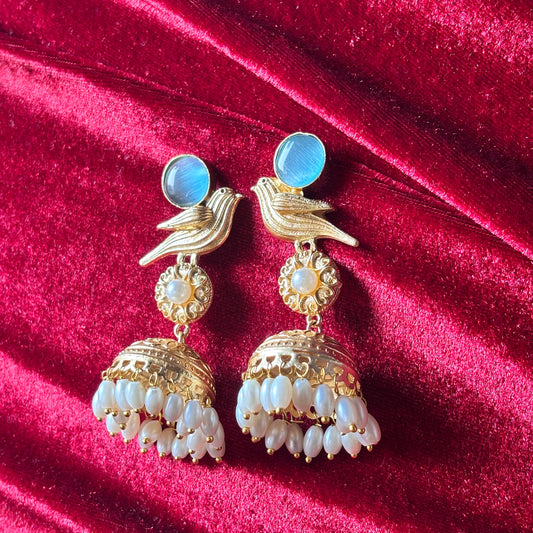 Gold and pearl earrings on a red velvet background