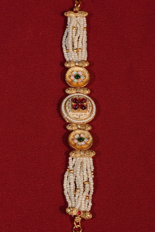 Decorative bracelet with gold and white beads on a red background