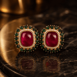 Halo stud earrings featuring red center cabochon, emerald green outer stones, gold-tone frame